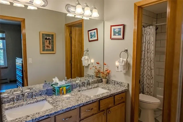 a bathroom with a granite countertop sink a toilet and a large mirror