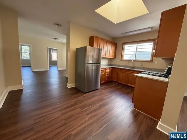 a kitchen with stainless steel appliances granite countertop a refrigerator a sink dishwasher a stove and white countertops with wooden floor