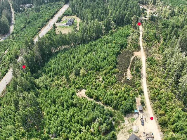 an aerial view of residential house with outdoor space and trees all around