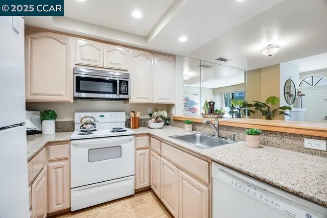 a kitchen with granite countertop white cabinets sink and stainless steel appliances