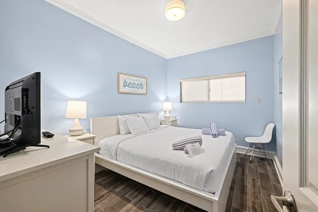 a bedroom with a bed and a flat tv screen on dresser