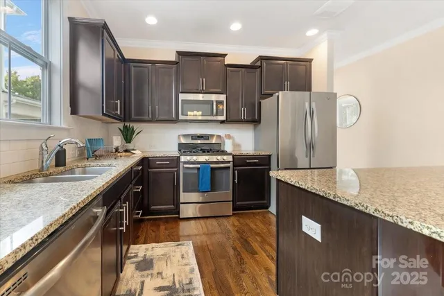 a kitchen with stainless steel appliances granite countertop a sink a stove and a refrigerator