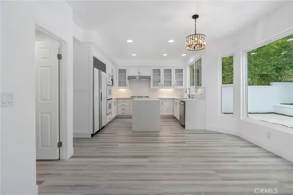 a view of a kitchen center island and stainless steel appliances wooden floor