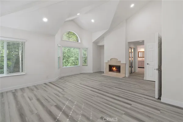 an empty room with windows and fireplace
