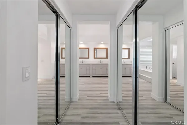 a view of a hallway with wooden floor and a bathroom