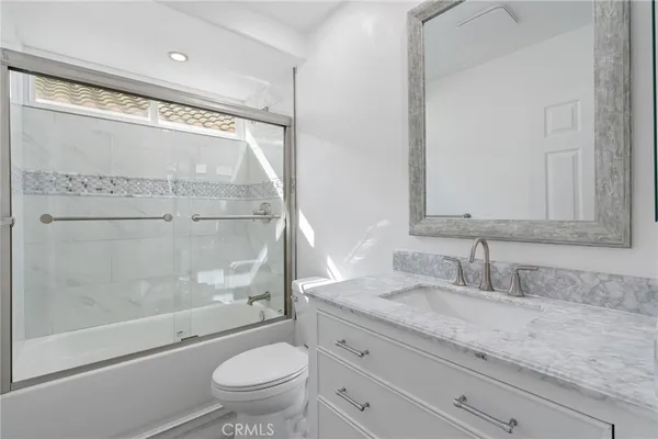 a bathroom with a granite countertop sink a toilet and shower
