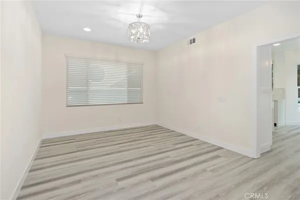 an empty room with wooden floor cabinet and windows