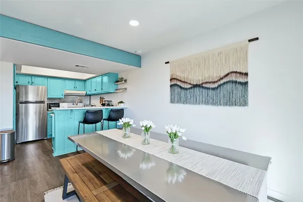 a kitchen with stainless steel appliances a refrigerator a stove a sink and a dining table with wooden floor