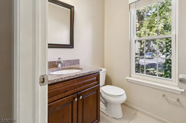 a bathroom with a granite countertop toilet a sink a mirror and a window