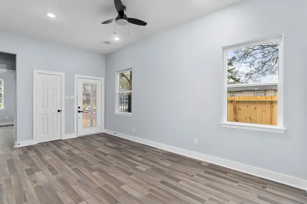 a view of an empty room with window and wooden floor