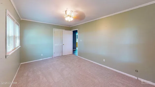 a view of an empty room with a chandelier fan
