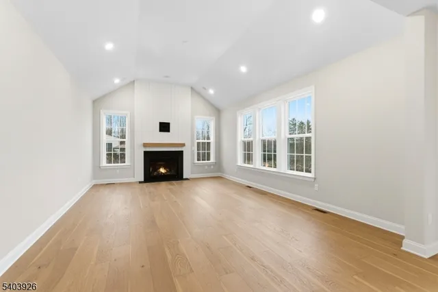 an empty room with wooden floor fireplace and windows