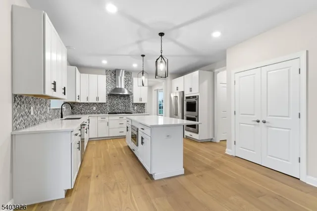 a large kitchen with stainless steel appliances granite countertop a stove a sink dishwasher and a refrigerator with wooden floor