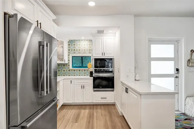 a kitchen with stainless steel appliances kitchen island granite countertop a dining table chairs and white cabinets