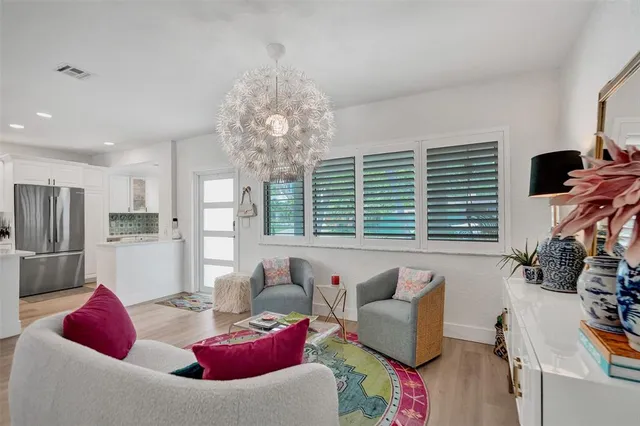 a kitchen with stainless steel appliances kitchen island granite countertop a refrigerator a stove and white cabinets with wooden floor