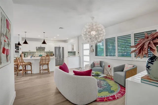a view of a dining room and livingroom with furniture wooden floor a rug a fireplace and a chandelier