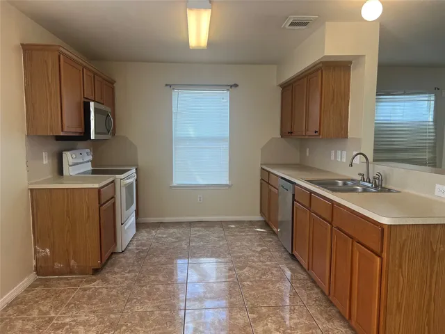 a kitchen with a sink stove top oven and wooden cabinets