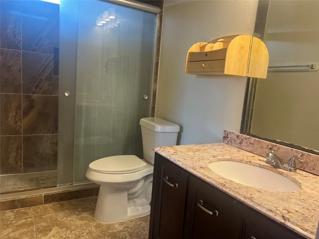 a bathroom with a granite countertop toilet sink and mirror