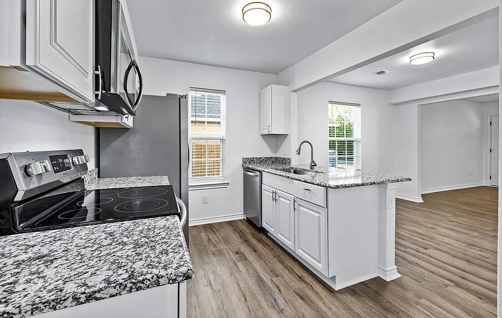 406 East Elm Street Denison, TX 75021 - Photo 6 of 21 a kitchen with granite countertop a stove and cabinets