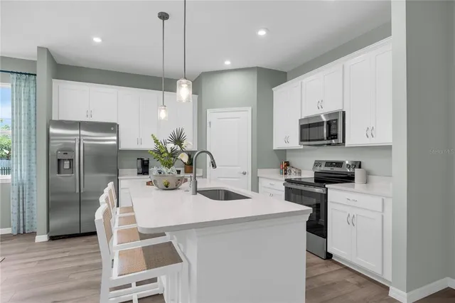 a kitchen with kitchen island a counter space a sink appliances and cabinets