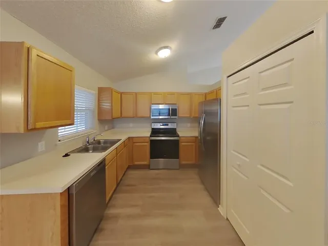a large kitchen with stainless steel appliances a sink and cabinets