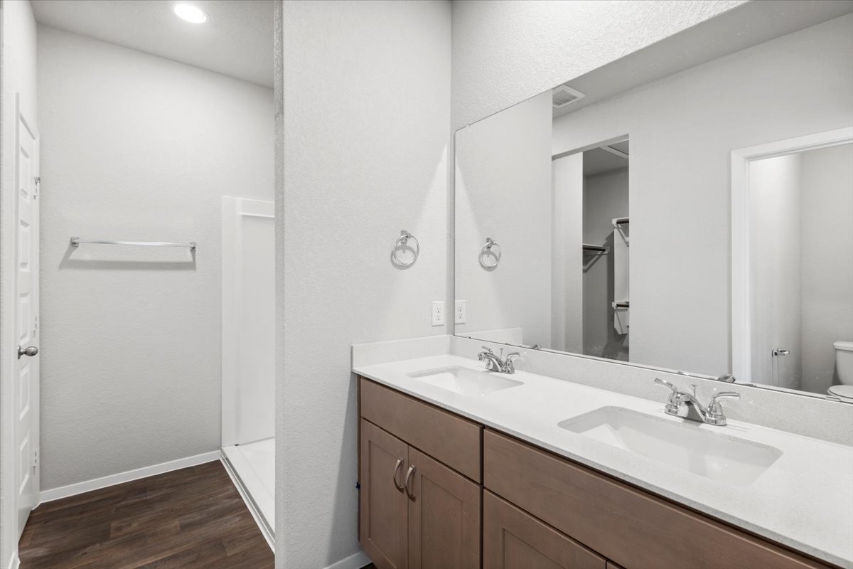 2607 Totley Road Manor, TX 78653 - Photo 17 of 40 Full bath with wood finished floors, double vanity, a walk in shower, and a walk in closet