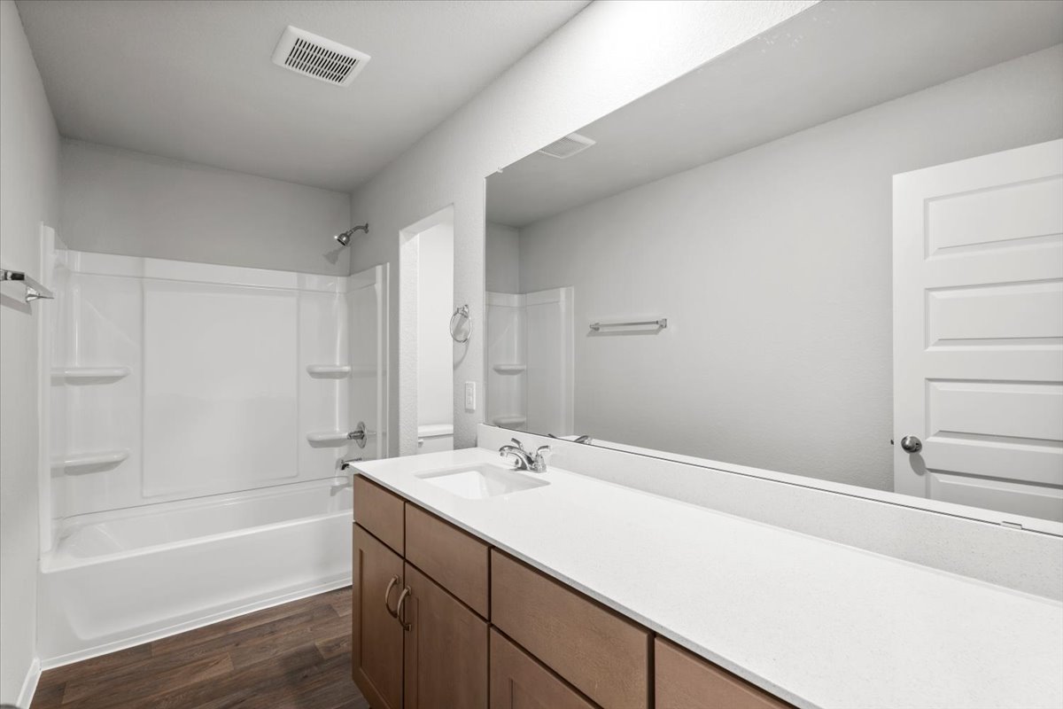 2607 Totley Road Manor, TX 78653 - Photo 30 of 40 Bathroom with vanity, wood finished floors, and washtub / shower combination