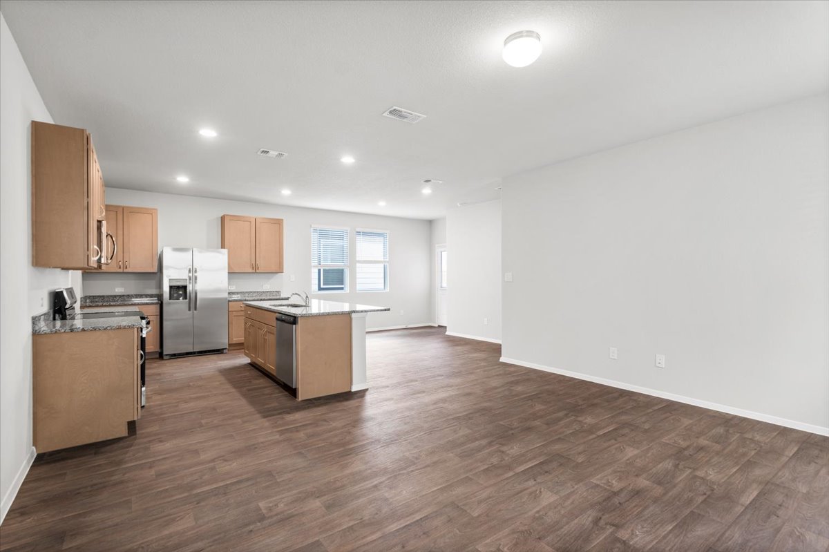 2607 Totley Road Manor, TX 78653 - Photo 40 of 40 Kitchen featuring appliances with stainless steel finishes, a kitchen island with sink, dark wood finished floors, open floor plan, and recessed lighting