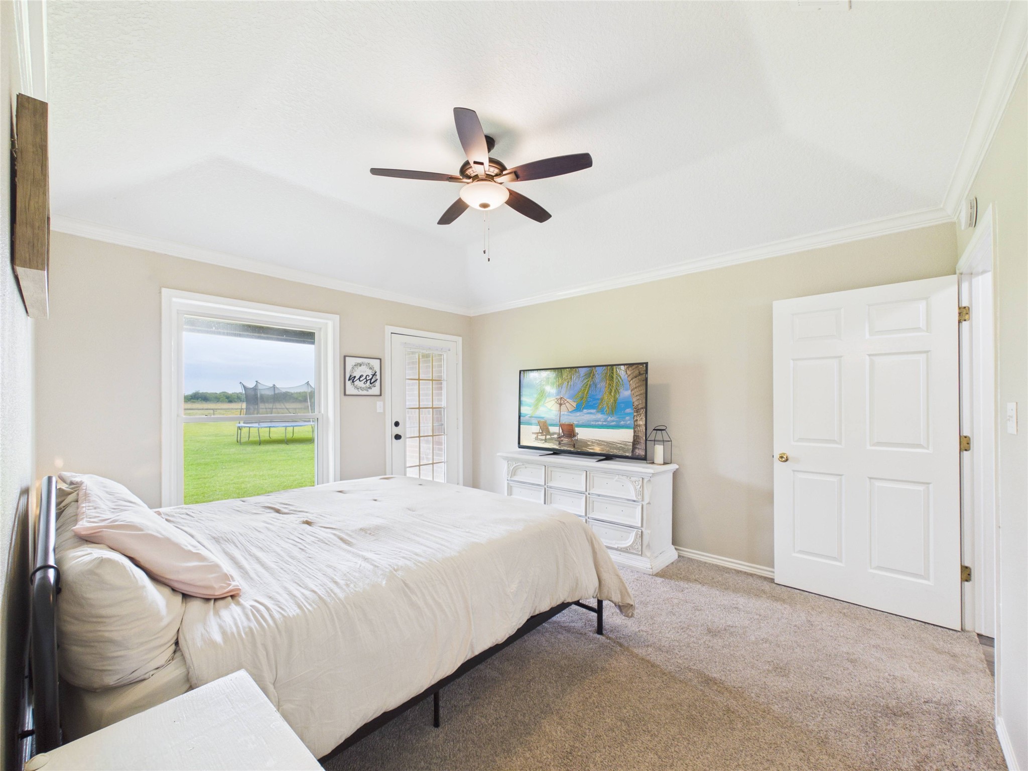 4610 Mustang Road Alvin, TX 77511 - Photo 29 of 50 Primary bedroom with picture window overlooking the back yard and a door to patio #2 that is just outside this room. Crown molding, updated fixtures, pocket door to the primary bathroom and walk in closet.