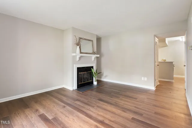 a view of empty room with wooden floor and fireplace