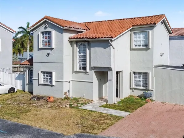 a view of a house with a small yard and large tree
