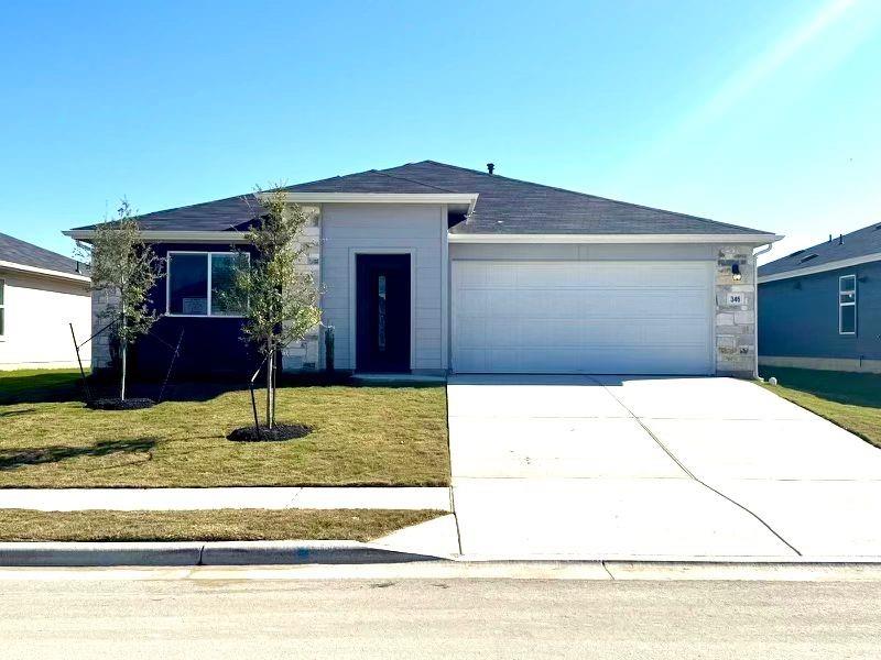 Ranch-style home featuring driveway, an attached garage, a front yard, and stone siding
