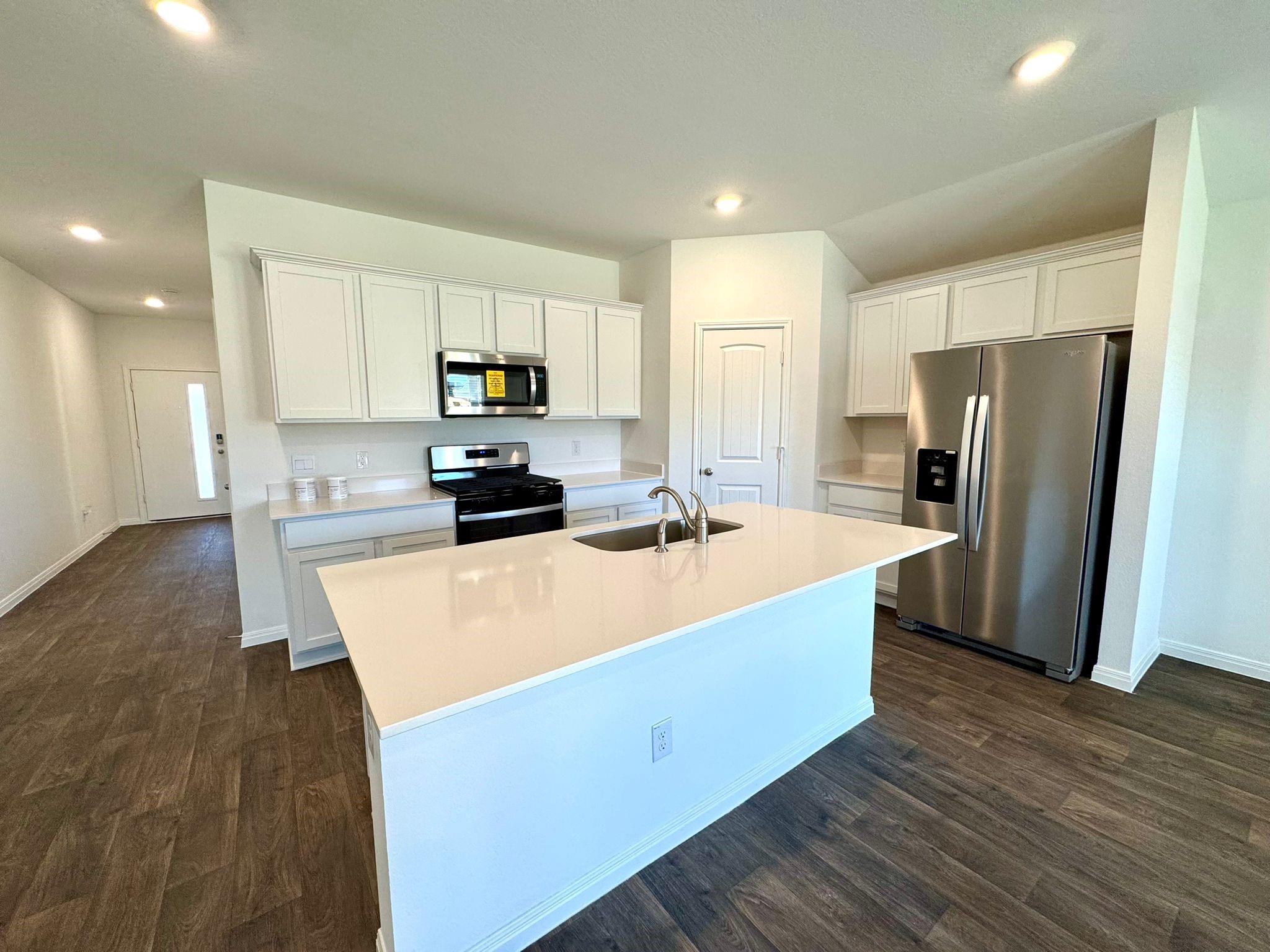 346 Gladiola Loop Kyle, TX 78640 - Photo 6 of 16 Kitchen with stainless steel appliances, white cabinets, an island with sink, dark wood-style flooring, and recessed lighting