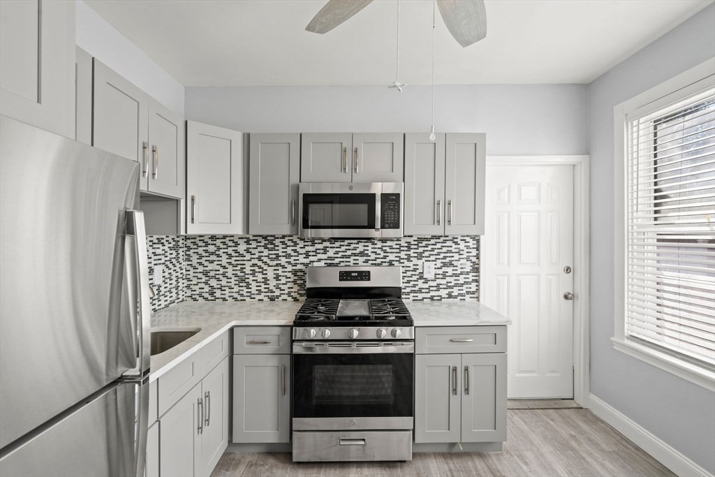 8 North Avenue, Unit 1 Boston, MA 02119 - Photo 1 of 15 a kitchen with white cabinets and stainless steel appliances