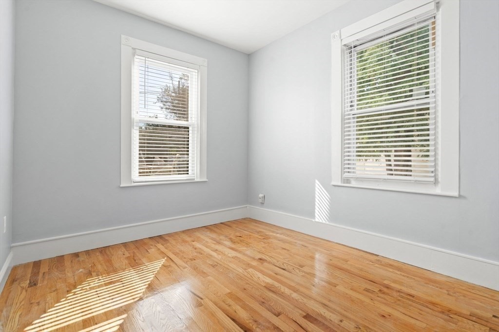 8 North Avenue, Unit 1 Boston, MA 02119 - Photo 12 of 15 a view of an empty room with wooden floor and a window