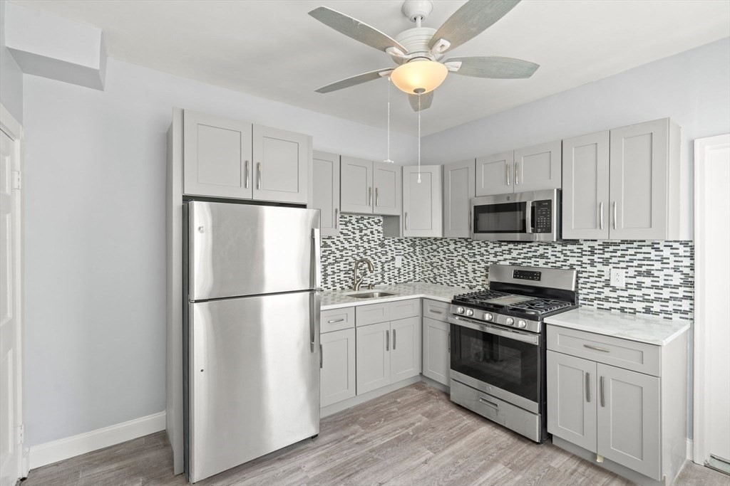 8 North Avenue, Unit 1 Boston, MA 02119 - Photo 2 of 15 a kitchen with stainless steel appliances a refrigerator sink and cabinets