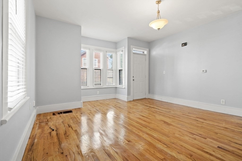 8 North Avenue, Unit 1 Boston, MA 02119 - Photo 7 of 15 a view of an empty room with wooden floor and a window