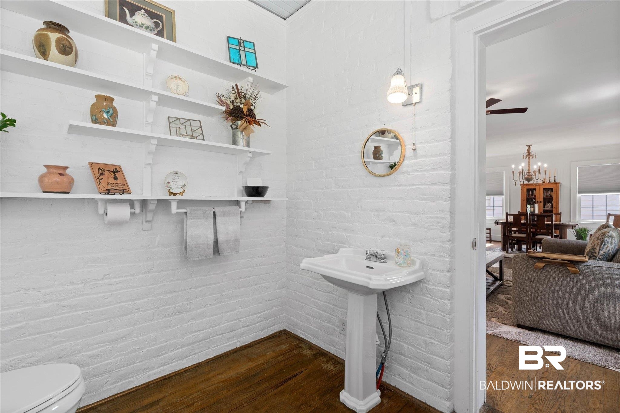 1910 Hunter Avenue Mobile, AL 36606 - Photo 17 of 21 Half bathroom with wood finished floors, brick wall, toilet, a chandelier, and a sink