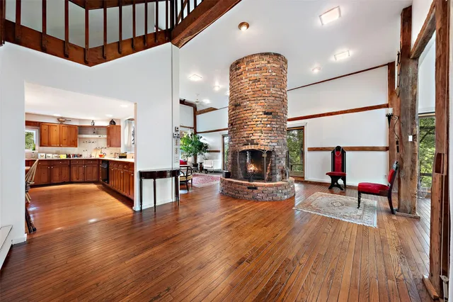 a living room with stainless steel appliances furniture wooden floor and a kitchen view