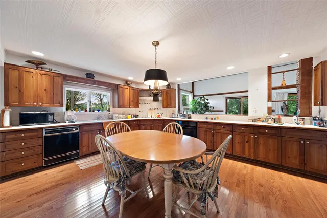 a kitchen with a dining table chairs stainless steel appliances and cabinets
