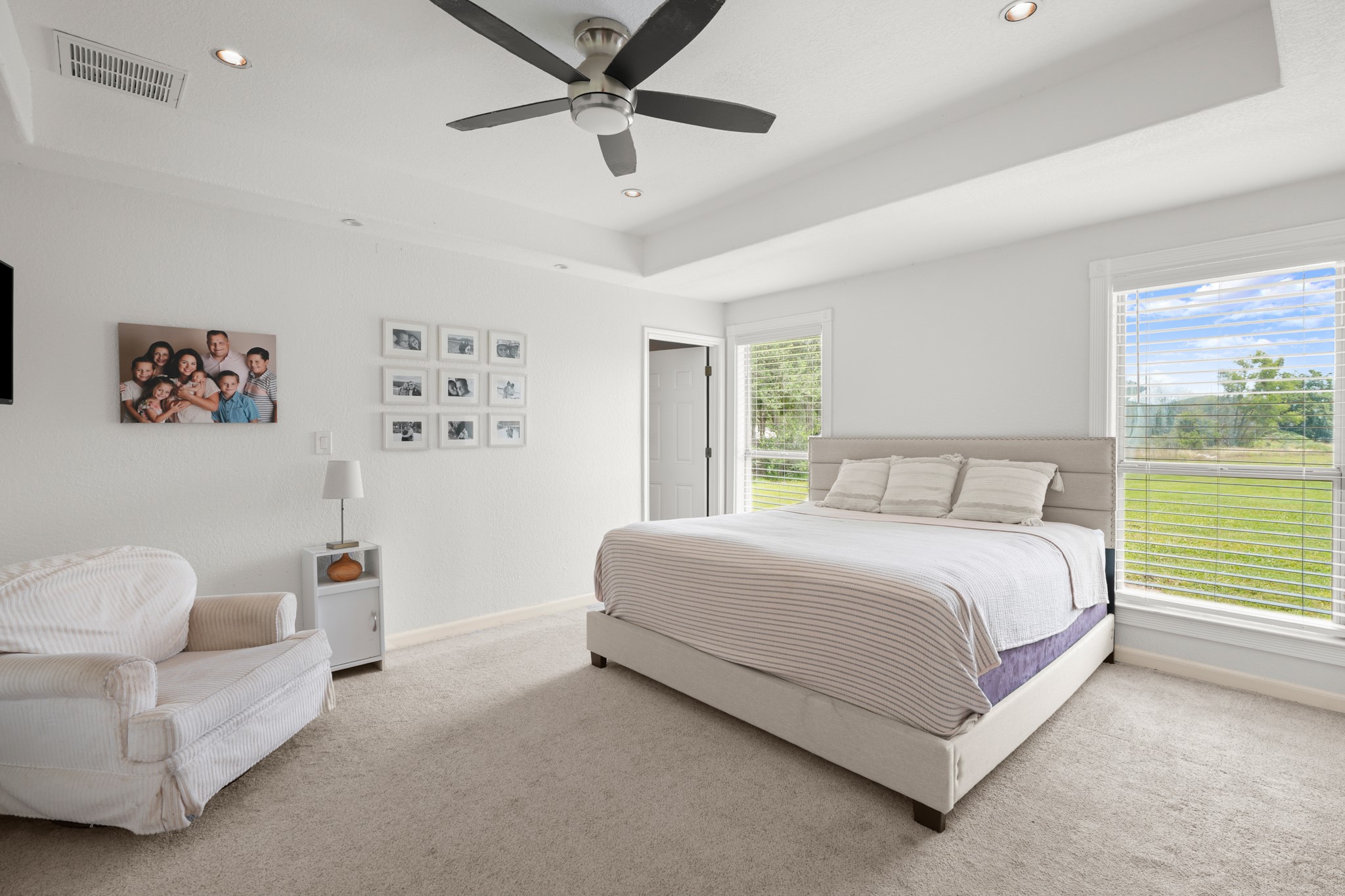 9725 Bock Road Buda, TX 78610 - Photo 20 of 32 Unwind in this restful primary bedroom, offering plush carpeting, dual windows, and a sophisticated tray ceiling.