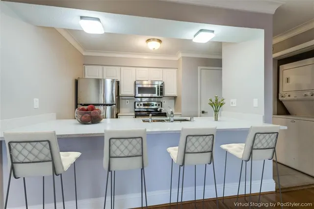a kitchen with stainless steel appliances a dining table chairs refrigerator and microwave