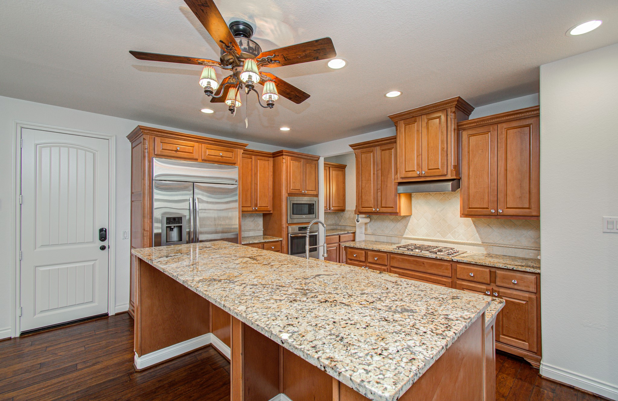 6621 North Main Street Houston, TX 77009 - Photo 11 of 41 Spacious kitchen featuring granite countertops, stainless steel appliances, wooden cabinetry, and a central island. It includes recessed lighting and a ceiling fan for added comfort and functionality.