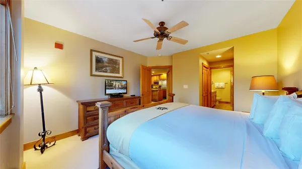 a bedroom with a large bed a chandelier and dresser