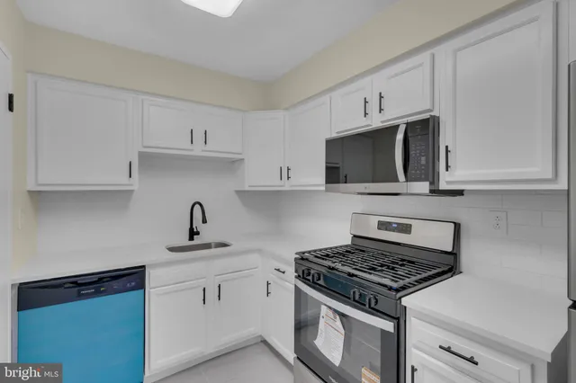 a kitchen with stainless steel appliances a sink dishwasher a stove and white cabinets