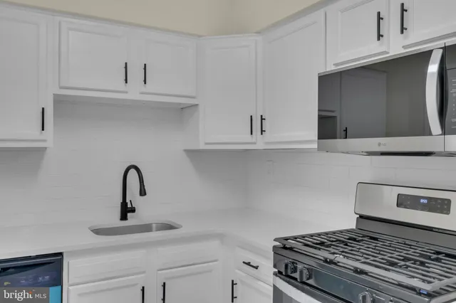 a kitchen with white cabinets and appliances