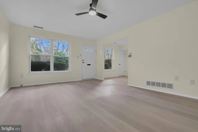 an empty room with wooden floor and windows
