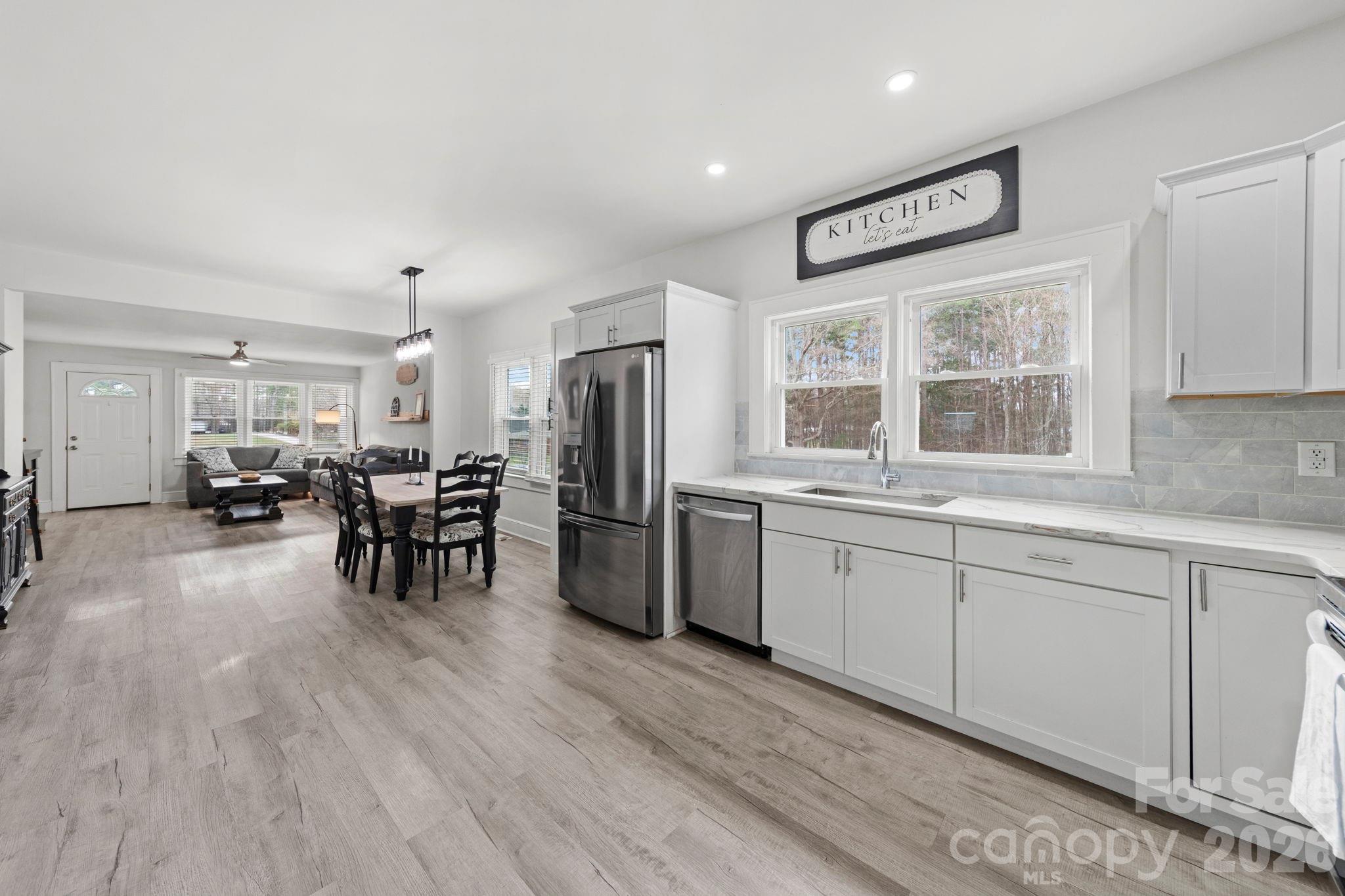 36141 Palestine Road Albemarle, NC 28001 - Photo 13 of 40 a open kitchen with stainless steel appliances granite countertop a stove top oven a refrigerator a dining table and chairs with wooden floor