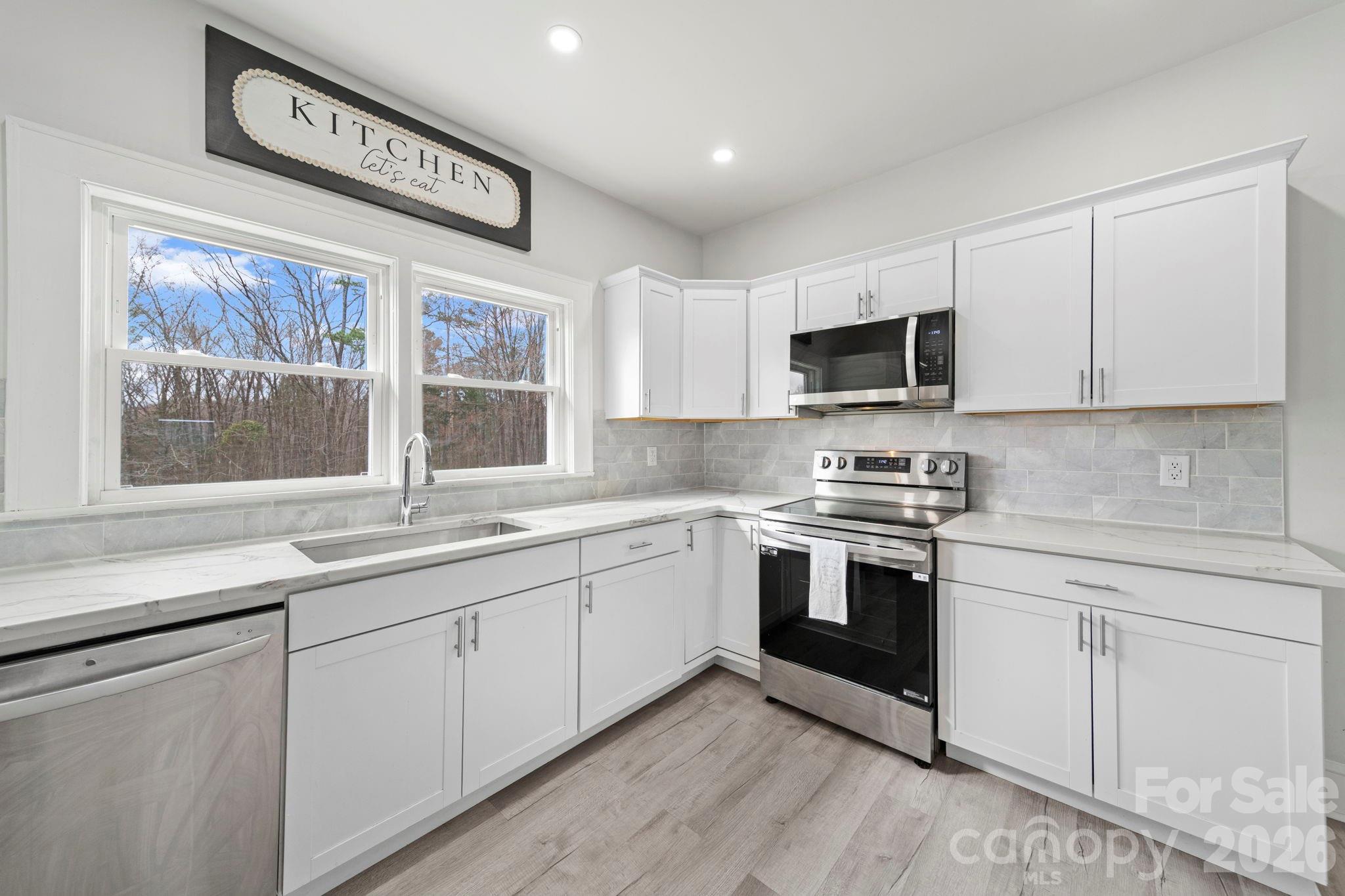 36141 Palestine Road Albemarle, NC 28001 - Photo 10 of 40 a kitchen with stainless steel appliances granite countertop a stove top oven a sink and dishwasher with white cabinets