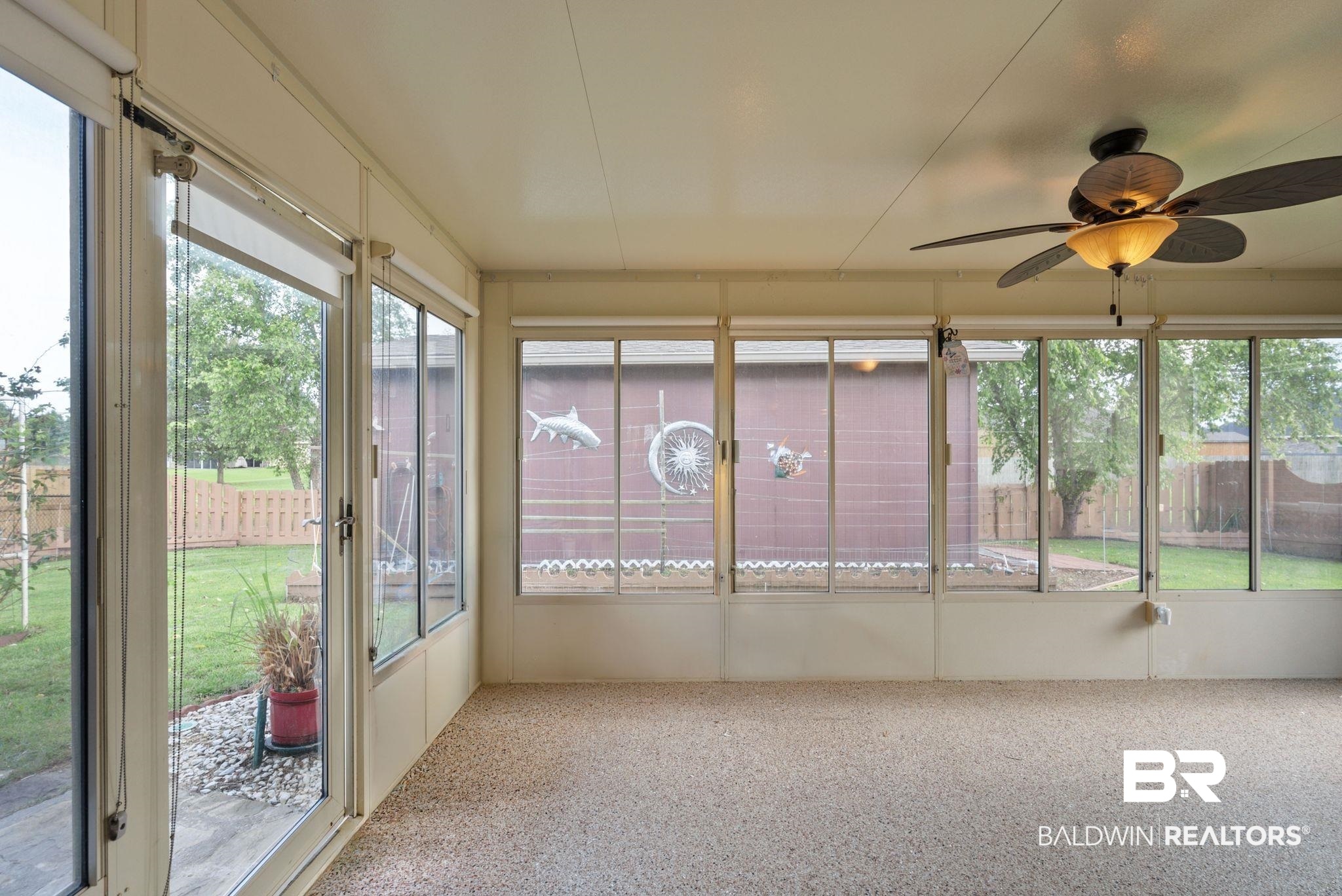 562 Vestige Mews Foley, AL 36535 - Photo 39 of 54 Screened patio featuring a ceiling fan with light fixture, full-height windows, a glass door providing access to the yard, and light-toned flooring